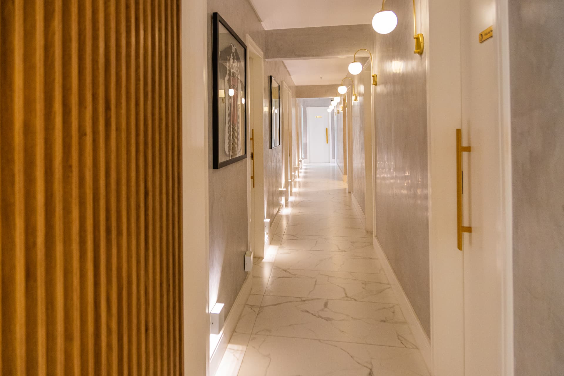 Corredor da clínica com painel de madeira e piso de mármore